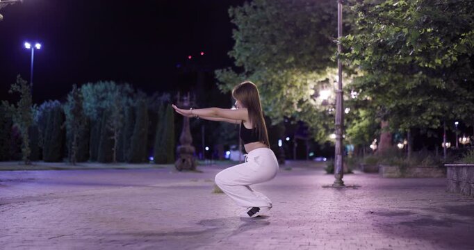 Young Asian woman practicing tai chi in a peaceful park at night