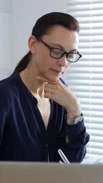 Businesswoman signing and reviewing accounting documents while calculating financial data in a corporate office setting. Audit and taxes in business