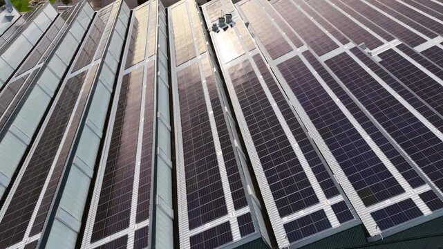 4k Aerial view solar panel facade on modern high rise with bright sun flare, glass and metal surfaces, strong geometric lines, clean energy architecture