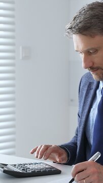 Focused businessman sitting at a modern desk, working intently on a laptop surrounded by folders, showcasing professionalism and determination. Audit and taxes in business
