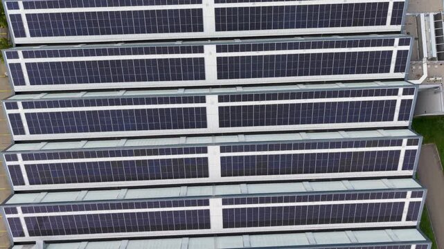 4k Aerial view solar panel facade on modern high rise with bright sun flare, glass and metal surfaces, strong geometric lines, clean energy architecture