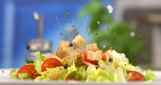 Croutons and spices falling onto fresh caesar salad slow motion 1000 fps