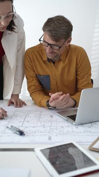 Architecture professionals collaborating on a housing project, studying detailed blueprints and a scaled 3d model, discussing design ideas for urban planning and modern construction