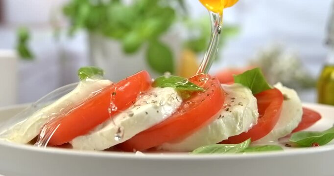 Sunflower oil pouring onto fresh caprese salad white kitchen background slow motion 1000 fps