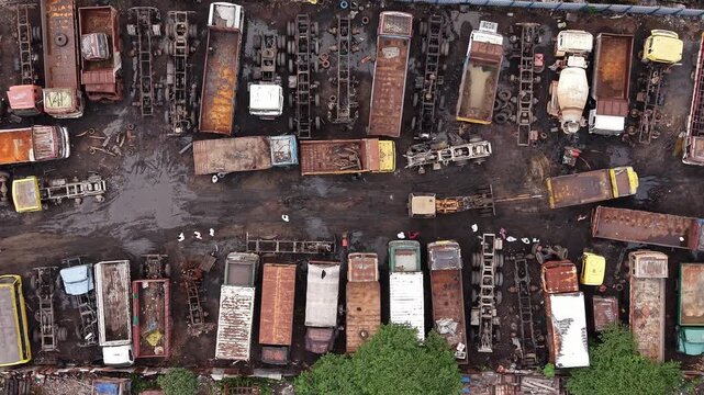 Aerial view of a truck scrapyard with numerous rusted vehicles, trailers, and chassis parked on muddy ground in Chennai, Tamil Nadu, India.