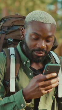A man with an adventurous spirit enjoys nature, using his smartphone and wearing a backpack