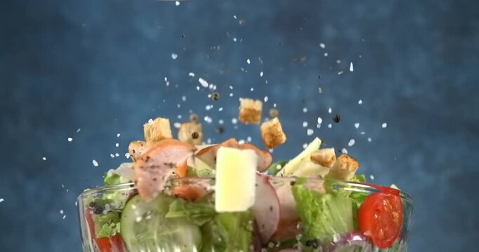 Chicken parmesan and seasonings falling into a fresh caesar salad bowl slow motion 1000 fps