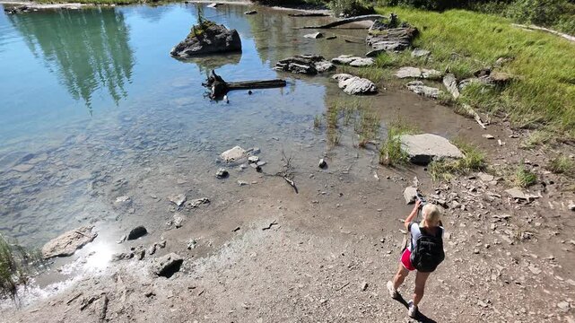 Woman standing on the rocky shore of Maligne Lake with turquoise water, enjoying the breathtaking views of Spirit Island and surrounding evergreen forests in Jasper National Park, Alberta, Canada