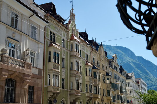 Traditional Alpine city facade with historic bay windows and mountain background