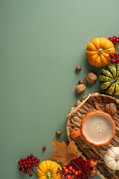 Autumn Thanksgiving still life with pumpkin mug, gourds, nuts and colorful leaves on vertical soft green background with copyspace