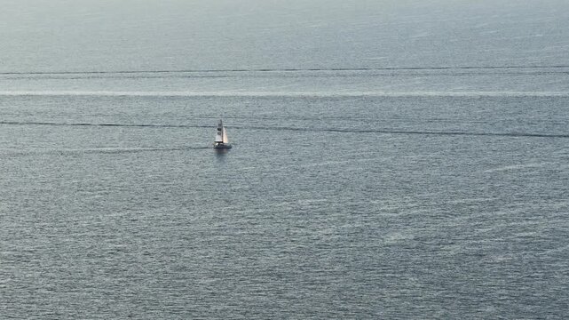 Aerial view of a small sailboat sailing on the calm blue waters of the Mediterranean Sea near the coastal area of Le Trayas in Saint-Raphael, Provence-Alpes-Cote d'Azur, France.