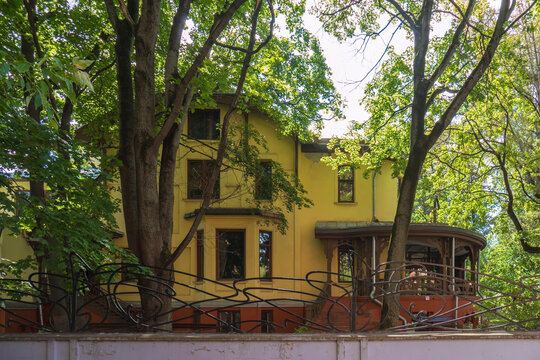 Historic twentieth century wooden art nouveau Nosov mansion facade hidden behind green trees in Moscow Russia