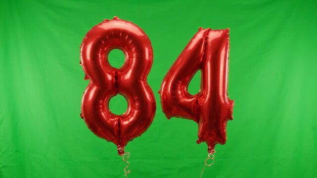 Red Foil Balloons Number 84 Floating On Green Screen