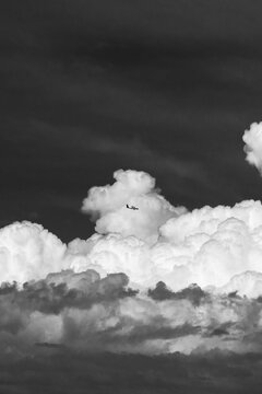 View of a small airplane flying against a backdrop of large, dramatic cumulus clouds in the sky over Costa Rica.