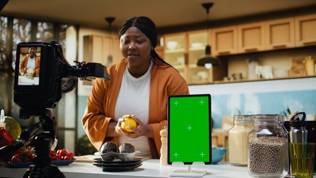 Black influencer films food vlog with green screen tablet