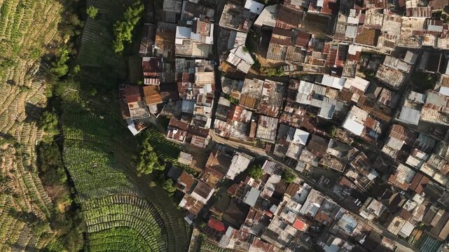 Aerial view of Kruwisan Village with dense housing and adjacent terraced agricultural fields in Kledung, Central Java, Indonesia.
