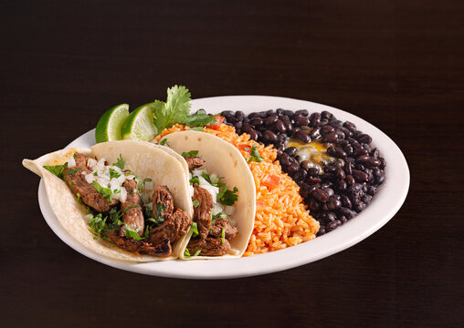 Taco platter with beef tacos, rice and black beans with melted cheese; copy space