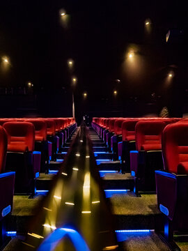 Empty cinema theater hall with red velvet seats and ambient floor lighting