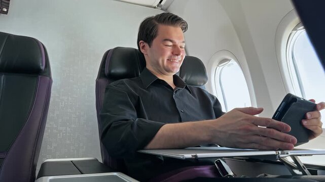 Happy Businessman Checking Stock Market Earnings on Tablet During Flight