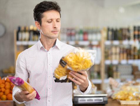 Mature man choosing pasta and spaghetti to cook an Italian dinner