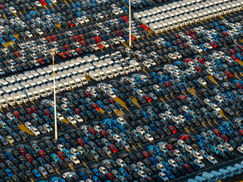 Aerial view of rows of new cars and vans parked in the automotive storage lot at Civitavecchia Port, with vehicles arranged in neat lines in Civitavecchia, Lazio, Italy.