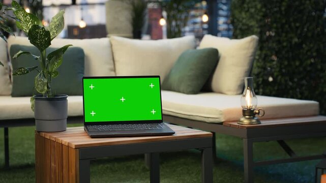 Close up of a green screen laptop on a rooftop lounge table with high rise buildings behind, providing a chroma key display above the business district.