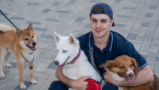 A man hugs his two dogs while on a walk. 