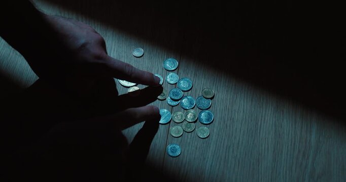 Person counts and organizes coins by hand on a table, representing savings, budgeting and personal finance.