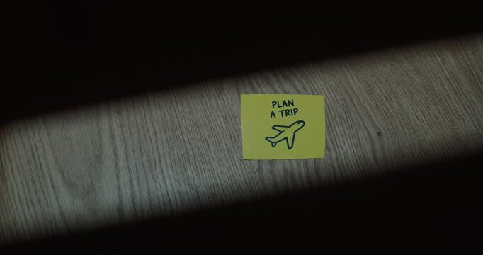 Plan a Trip sticky note with airplane symbol on a table, representing travel planning, vacation and future journey.