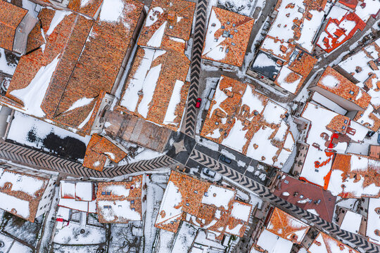 Aerial view of snow-covered terracotta rooftops and narrow streets in Pescocostanzo, Abruzzo, Italy.