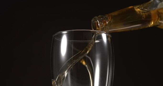 Beer pouring from glass bottle into mug in slow motion