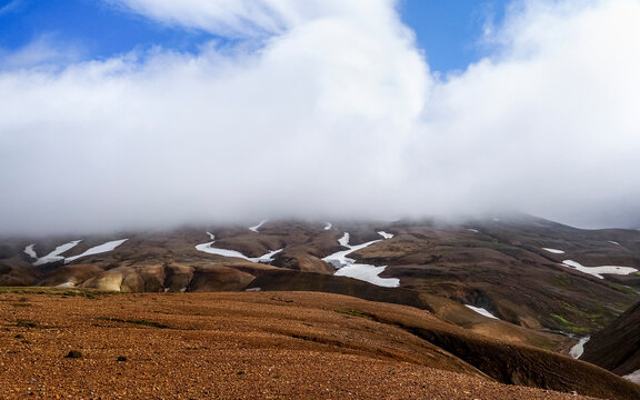 Wild Icelandic landscape and blue sky with white clouds. Colorful Kerlingarfj&ouml;ll Highlands. Snowy mountain peaks, deep gorges and Hveradalir geothermal area. Iceland, Hrunamannahreppur municipality.