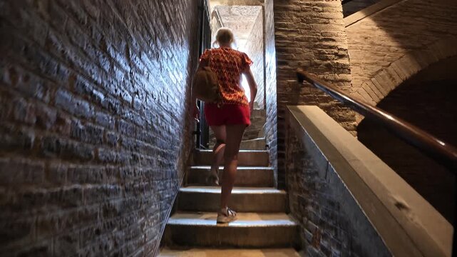 Breathtaking view of tourist woman inside the Ghirlandina bell tower of the Modena cathedral, showcasing its medieval architecture and complex structure of Modena city in Italy