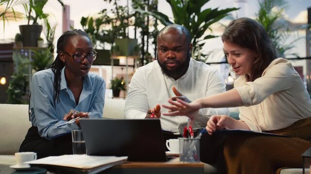 Businesspeople react positively to strong performance metrics on a laptop during a rooftop meeting, reviewing good KPI results together as a team.