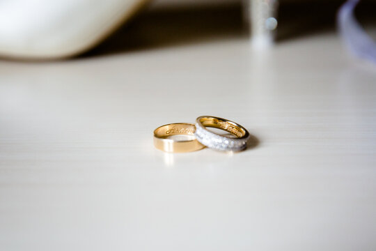 Two gold wedding rings with diamonds on light surface