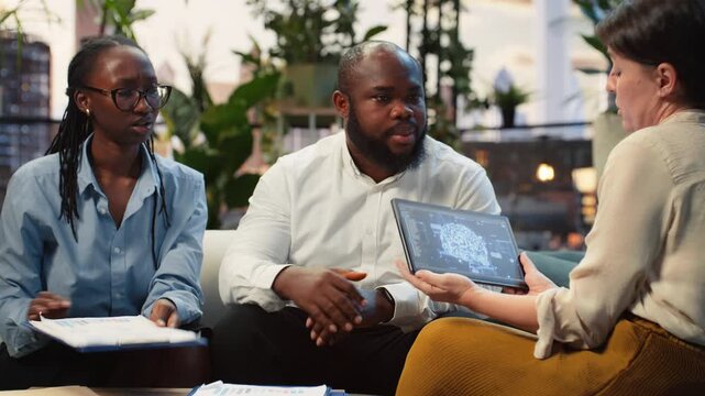 Close-up shows businesspeople using an AI model on a tablet during a rooftop strategy meeting, with colleagues applying deep learning technology during brainstorming above the business district.