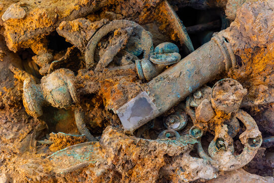 Close-up view of heavily corroded Celtic metal artifacts, oxidized bronze and iron parts embedded in compacted earth during archaeological excavation