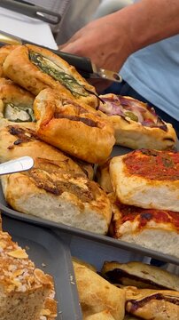 Close up camera motion over traditional Spanish Valencian cocas savory pastries with various toppings like tomatoes onions and vegetables at Festival Gastronomic in  Spain.