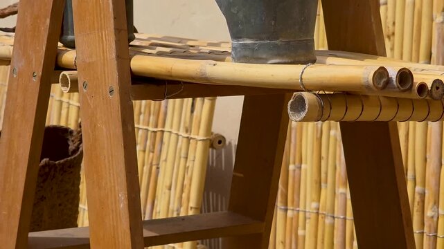 Close up pan view of antique traditional winemaking and agriculture tools, wicker demijohn bottles, wooden mallets, and metal shears displayed on cane shelves during the la Escalda festival in Spain.