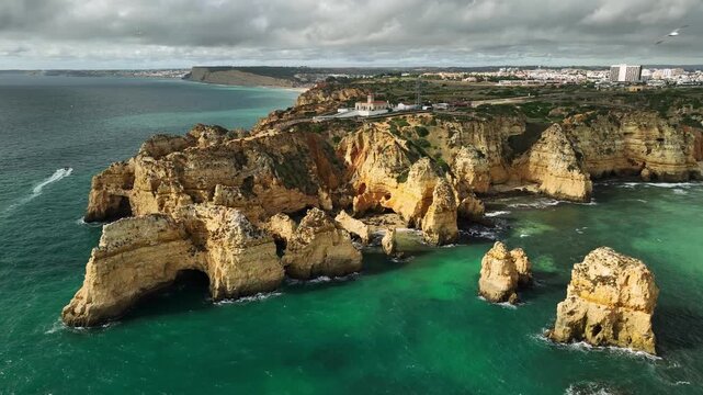 Drone view of Ponta da Piedade in Lagos, Algarve, Portugal, with sea stacks, ocean edge and limestone cliffs. Orbit parallax shot.