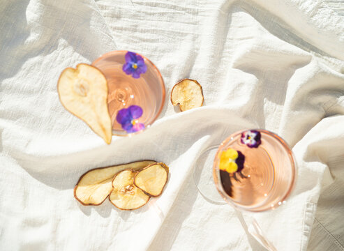 Minimalist still life with wine, dried fruits and edible flowers in soft sunlight.