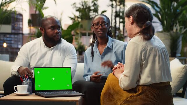 Business team uses a green screen laptop on a rooftop workspace table, with the mockup notebook supporting project discussion and a client presentation during the business meeting with coworkers.