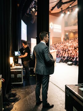 businessman waiting backstage before entering conference stage with large audience and camera crew