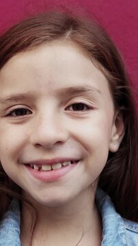 Happy redhead girl laughing in closeup on pink background - Childhood portrait concept - Vertical video