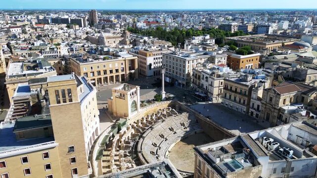 Aerial view of the ancient Roman Amphitheatre surrounded by historic stone buildings and urban architecture in Lecce, Apulia, Italy.