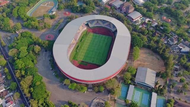 Aerial view of Manahan Stadium with its green pitch and surrounding trees and tennis courts in Surakarta, Central Java, Indonesia.