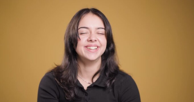 Young woman laughing joyfully in a casual setting on a warm-colored background