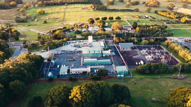 Aerial view of an industrial facility and power substation surrounded by macadamia orchards and farmland in Byron Bay, New South Wales, Australia.
