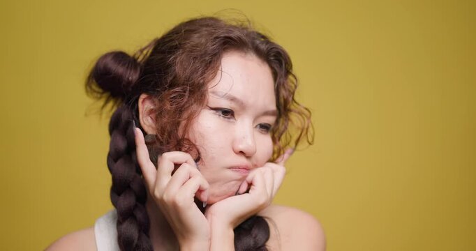 Young woman with braided hair looking puzzled against a yellow background