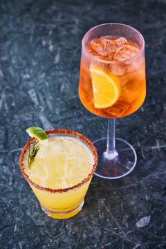 Pool drinks, margarita and Aperol Spritz over a black marbled surface.